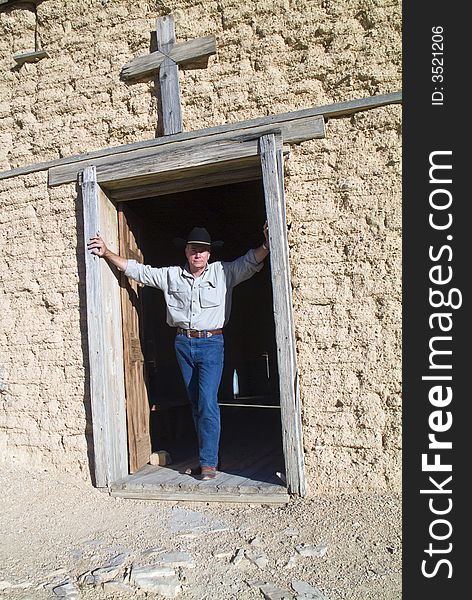 A man standing in the entrance to an old weathered adobe church building. A man standing in the entrance to an old weathered adobe church building.