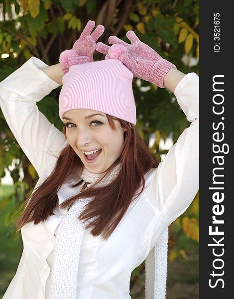 A beautiful woman with a red hair, white scarf, and pink bonnet and gloves. A beautiful woman with a red hair, white scarf, and pink bonnet and gloves.