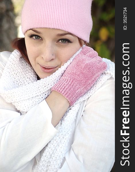 A beautiful woman with a red hair, white scarf, and pink bonnet and gloves. A beautiful woman with a red hair, white scarf, and pink bonnet and gloves.