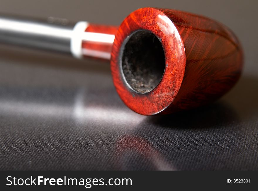 Red textured smoking pipe at black background