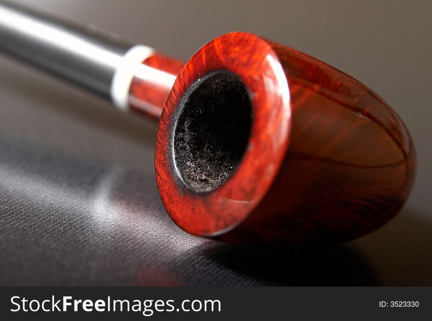 Red textured smoking pipe at black background