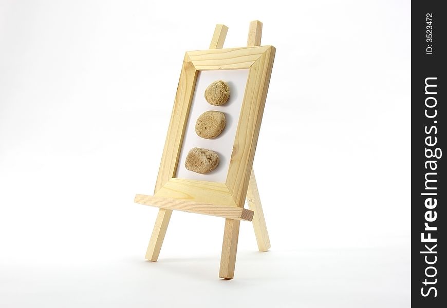 Wooden frame with three rocks on white background