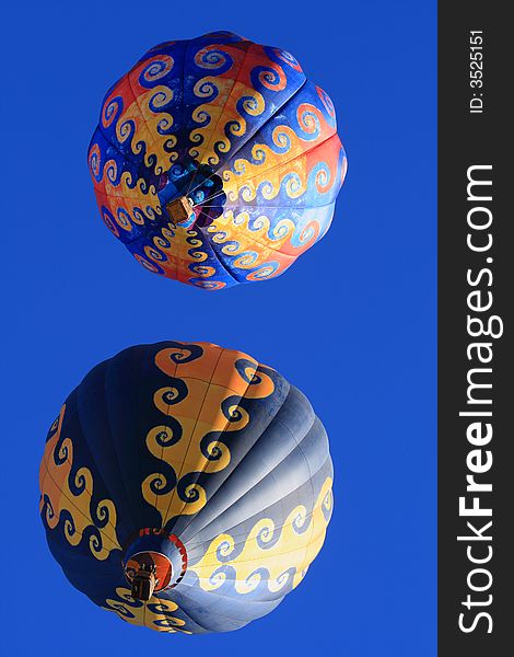 Two colorful hot air balloons in a blue sky