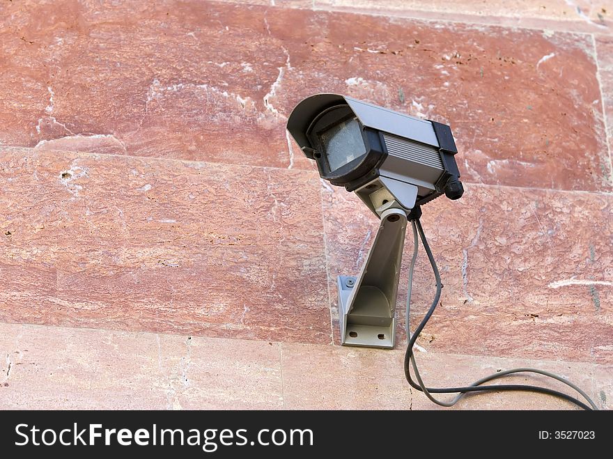 Security camera mounted on pink stone wall