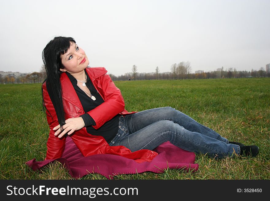 Black head woman is sitting on a Plaid in park grass