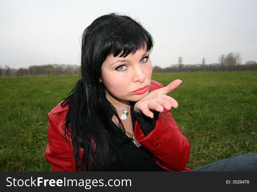 Woman show a kiss in park, sitting on grass