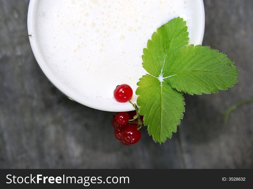 Cup with milk and red currant and leaf