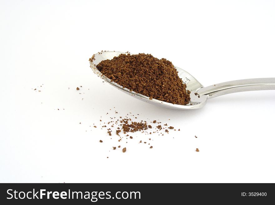 Coffee on silver spoon and white background.