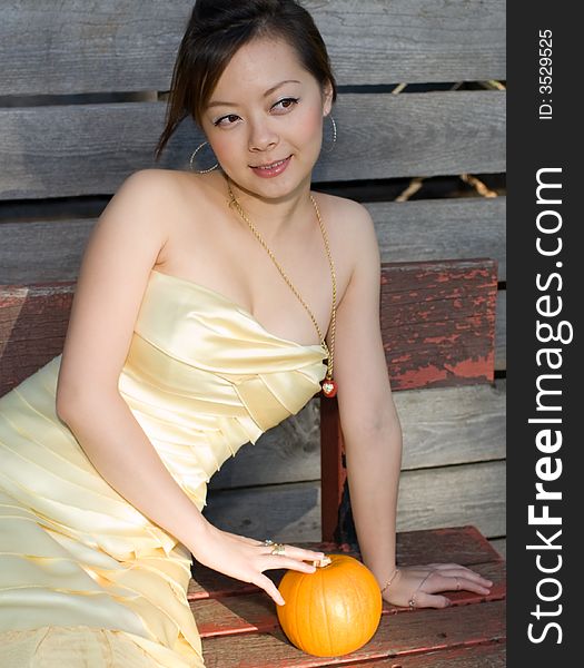 A girl sitting in long chair with a pumpkin. A girl sitting in long chair with a pumpkin