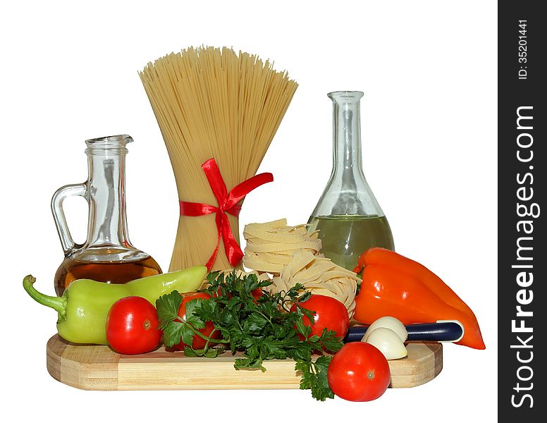 Pasta, tomatoes, pepper,greens and olive oil on a cutting board