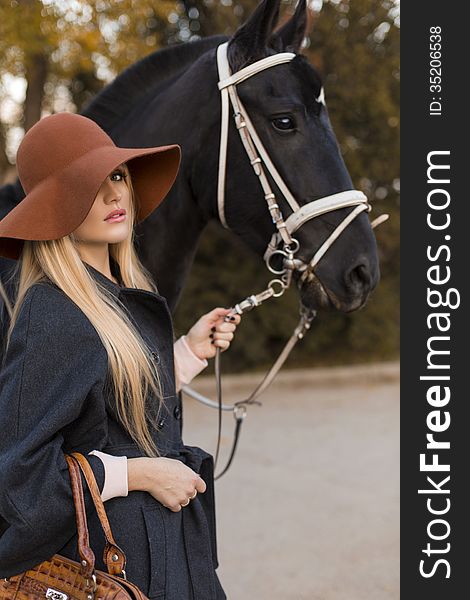 Beautiful girl with blond hair and black horse. Beautiful girl with blond hair and black horse