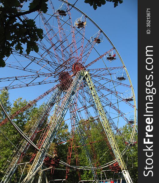 Photo with the image of the Ferris wheel is in the park in the summer.