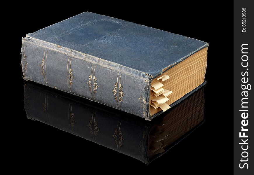 The closed ancient book in dark blue cover on a black background