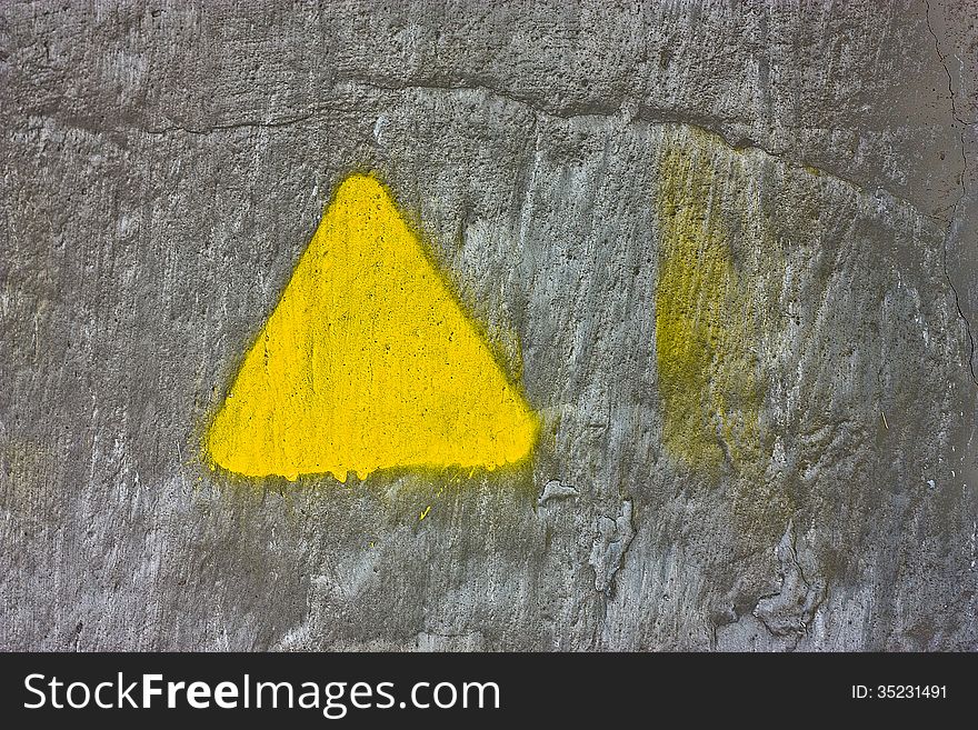 Concrete gray wall with yellow triangle