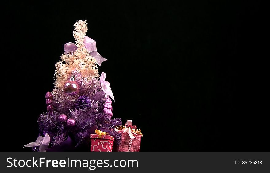 Decorated pink Christmas tree rotates on a black background