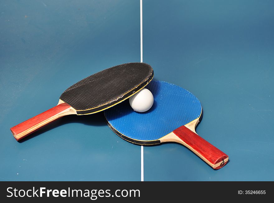 Blue and Black Table Tennis paddles and ball on table tennis table. Blue and Black Table Tennis paddles and ball on table tennis table