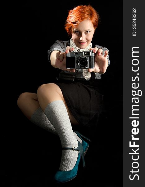 Red hair girl holding an old camera on black background. Red hair girl holding an old camera on black background