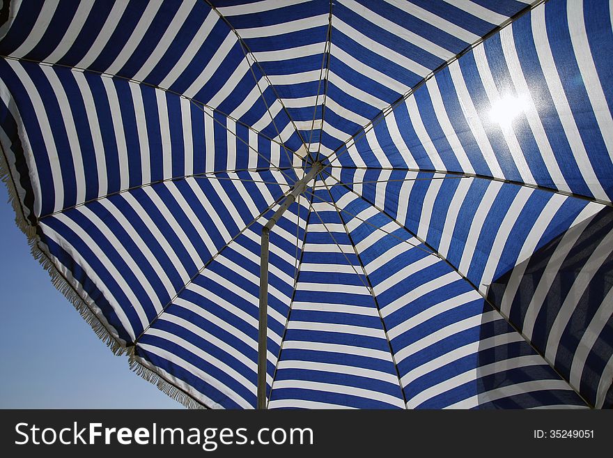 Umbrella in blue and white, under the sun