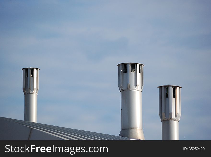 Some modern chimneys on top of a recent building