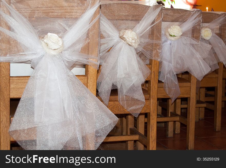 Wedding decoration on chairs with white roses.