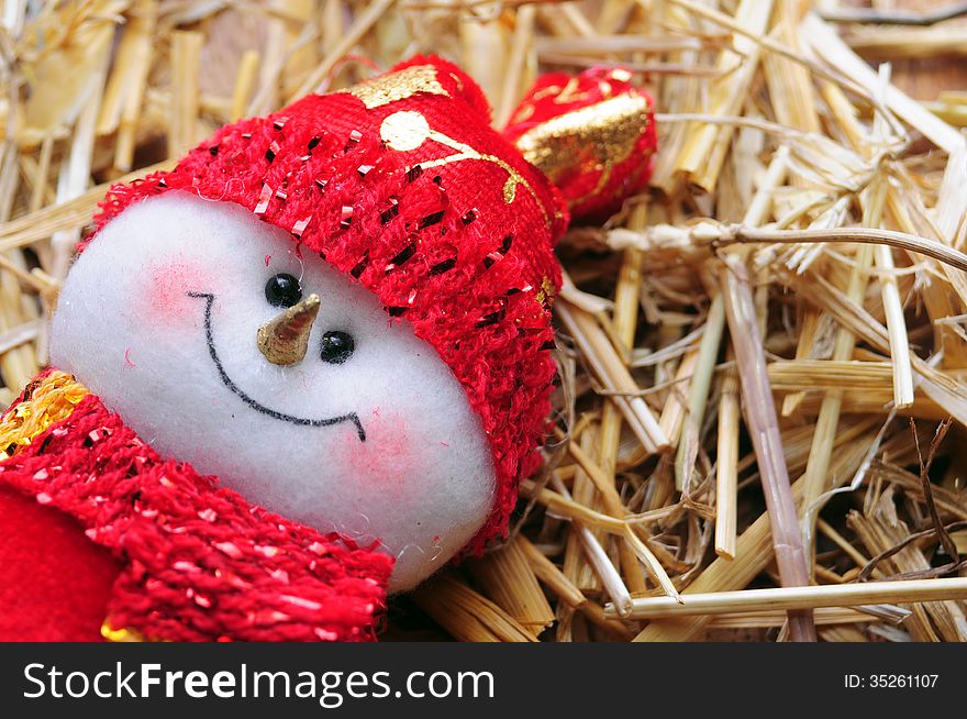 Red dressed puppet snowman over straw. Red dressed puppet snowman over straw