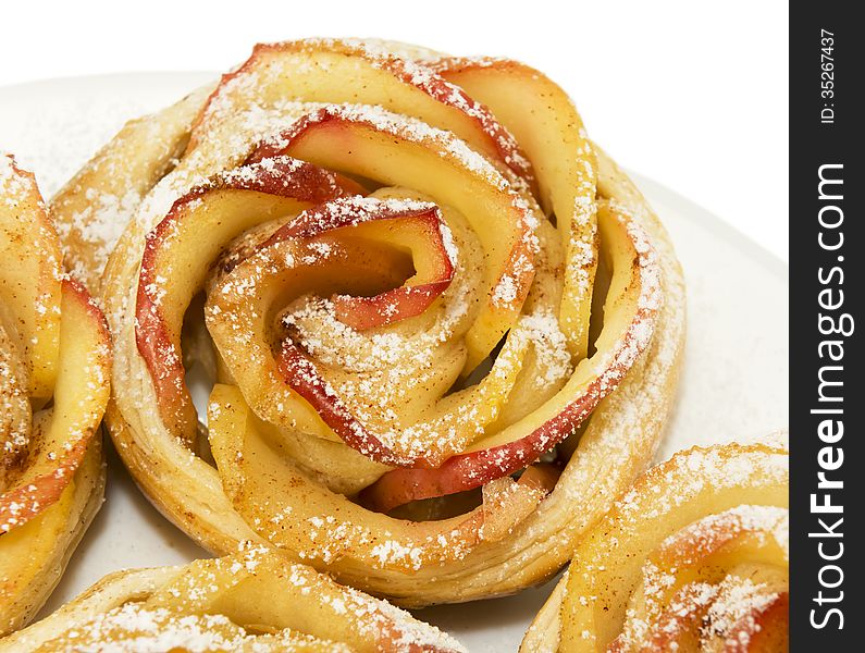 Sweet rolls with apples in the form of roses on plate on white isolated background. Sweet rolls with apples in the form of roses on plate on white isolated background