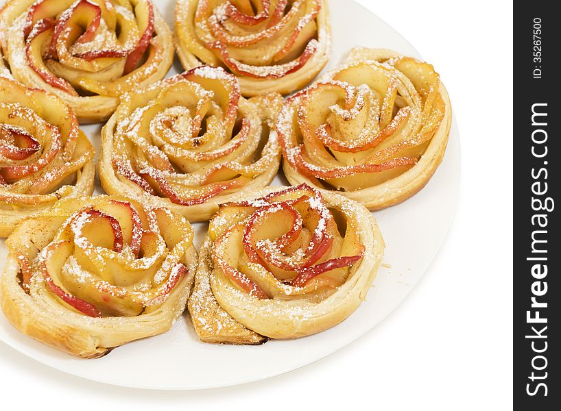 Sweet rolls with apples in the form of roses on plate on white isolated background. Sweet rolls with apples in the form of roses on plate on white isolated background