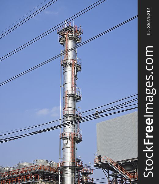 High distillation tower behind cable line in sunny day. High distillation tower behind cable line in sunny day