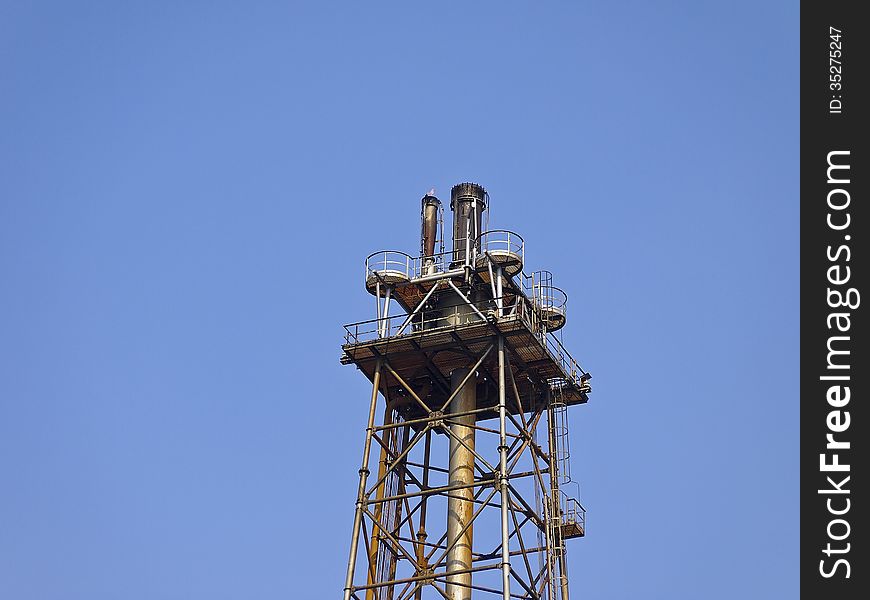 Peak of distillation tower in sunny day and blue sky