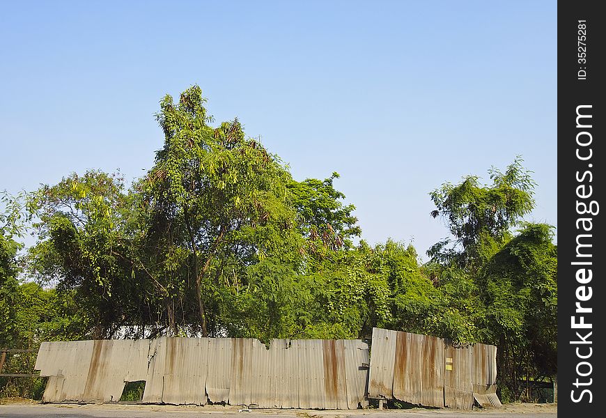 Old fence at side of secluded road in sunny day. Old fence at side of secluded road in sunny day