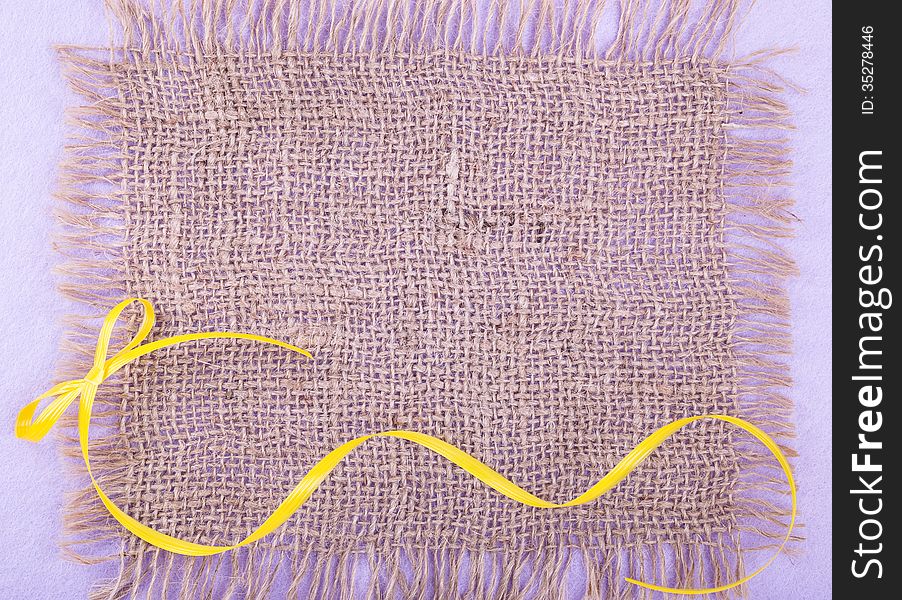 Burlap patch over lilac felt backdrop with yellow ribbon. Burlap patch over lilac felt backdrop with yellow ribbon