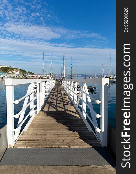 White wooden jetty walkway to marina with blue sky and clouds on summer day