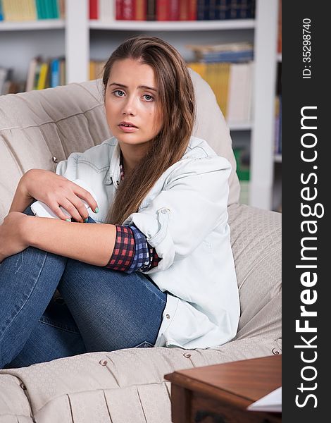 Young girl is crying sitting on the couch