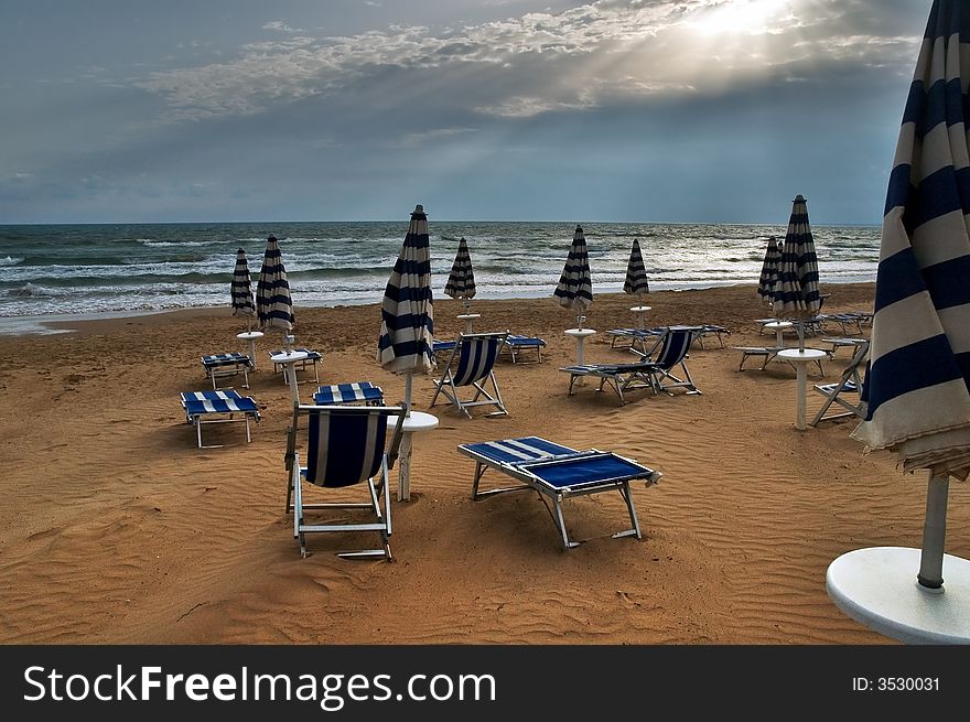 Beach with deckchairs, umbrellas and dramatic sky. Beach with deckchairs, umbrellas and dramatic sky