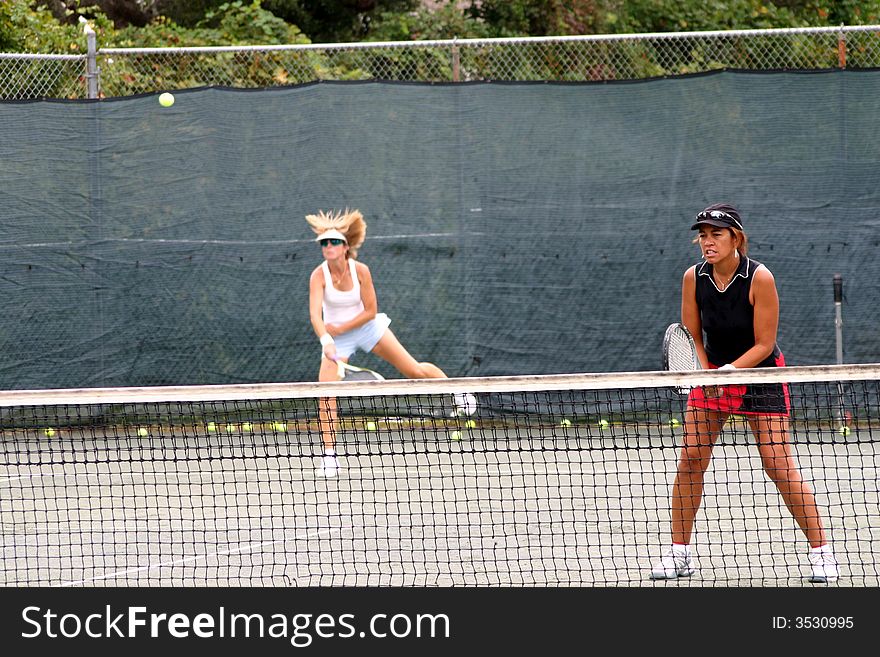 Two female tennis players playing doubles, one ethnic player. Two female tennis players playing doubles, one ethnic player