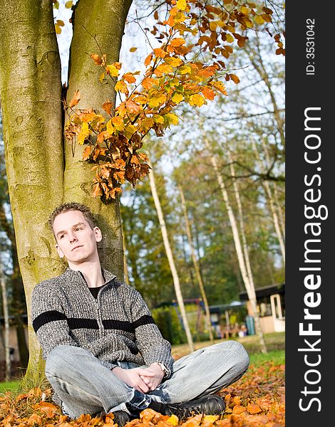 Boy in autumn colors is sitting an enjoy the sun. Boy in autumn colors is sitting an enjoy the sun