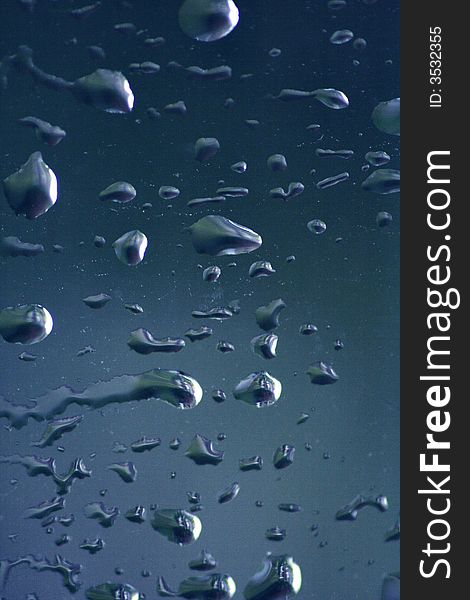 Rain drops moving across window with blue background. Rain drops moving across window with blue background