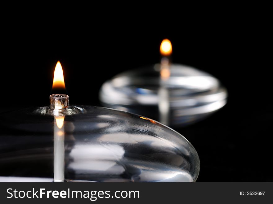 Close-up of two oval glass candles using selective focus. The one in the foreground is in sharp focus while the one in the back is out of focus.
