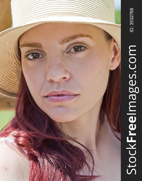 Closeup of the face of a beautiful young woman wearing a spring or summer hat. Closeup of the face of a beautiful young woman wearing a spring or summer hat.