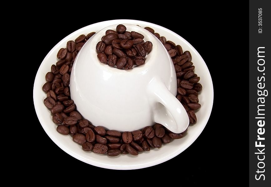 Upside down coffee mug sitting on a matching saucer with coffee beans around and on top of it.