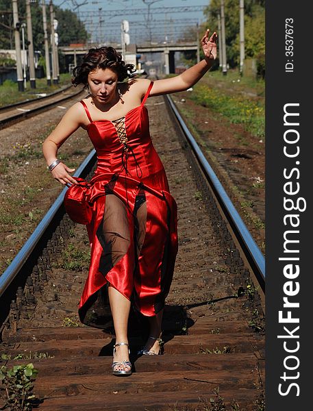 Girl in evening clothes hurry on rails. Girl in evening clothes hurry on rails