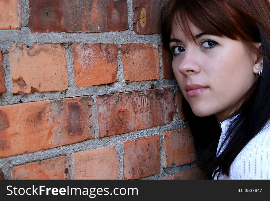 Girl leaning against a red brick wall. Girl leaning against a red brick wall