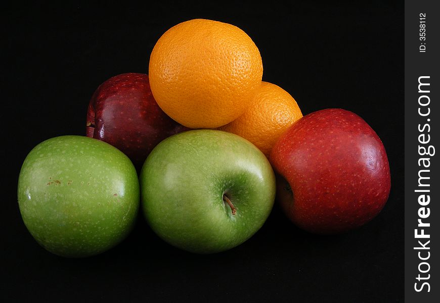 Granny Smith and Jonathan apples and navel oranges against a black background. Granny Smith and Jonathan apples and navel oranges against a black background.