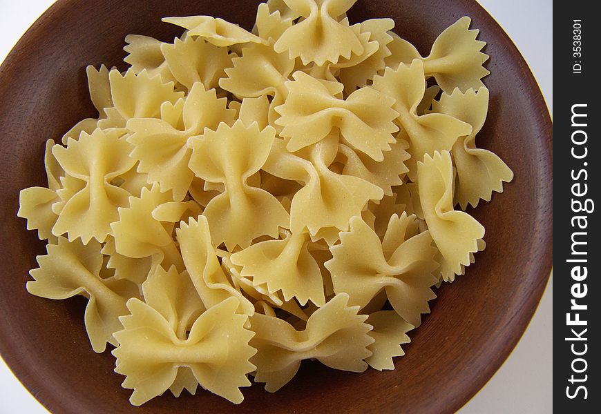 Close up of raw uncooked farfalle bowtie pasta in wooden bowl. Close up of raw uncooked farfalle bowtie pasta in wooden bowl