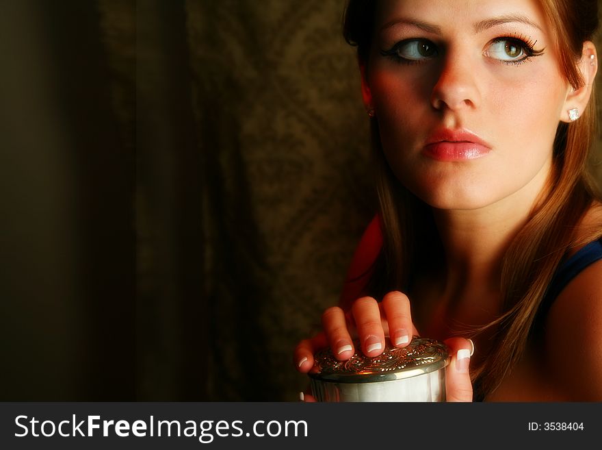 Beautiful young woman holding antique jar of facial powder. Beautiful young woman holding antique jar of facial powder.