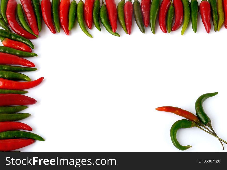 Red and green hot pepper as a framework on a white sheet. Red and green hot pepper as a framework on a white sheet