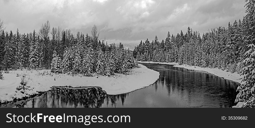 This black and white image of the stream with snow covered trees on both sides was taken in Glacier National Park, Montana. This black and white image of the stream with snow covered trees on both sides was taken in Glacier National Park, Montana.