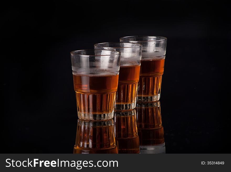 Three shot glasses full of dark colored alcohol on top of a bar table. Three shot glasses full of dark colored alcohol on top of a bar table.