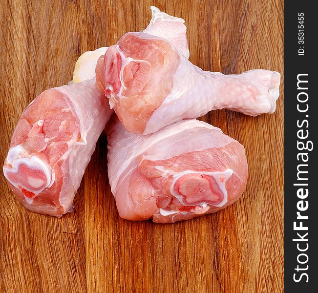 Three Raw Chicken Drumsticks closeup on Dark Wooden background. Three Raw Chicken Drumsticks closeup on Dark Wooden background