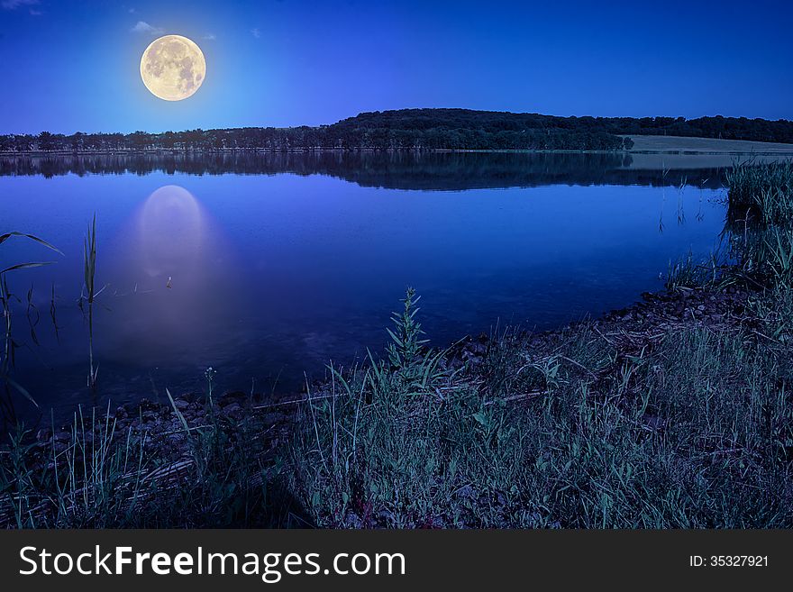 Mountain lake and forest on the embankment at night. Mountain lake and forest on the embankment at night